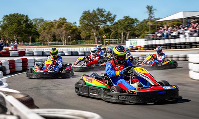 Collega's racen in karts op een buitenbaan tijdens een teambuildingdag