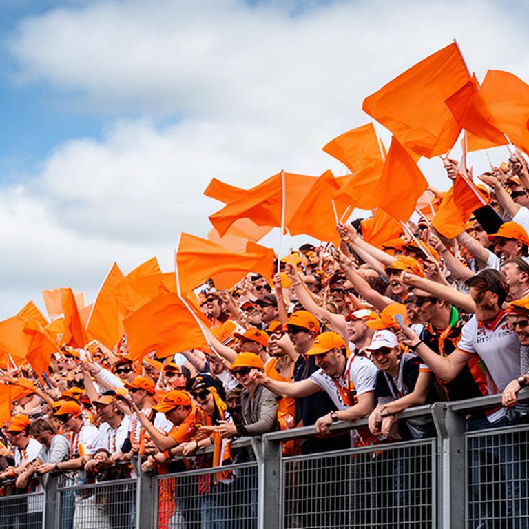 Fans met vlaggen en petten in een vol oranje vak op de tribune van Zandvoort